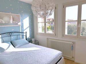 GARDA BLUE HOME on the lake - pool, solarium and garage في توسكولانو ماديرنو: غرفة نوم بسرير وثريا ونافذتين