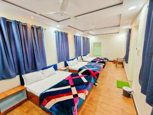 a row of beds in a room with blue curtains at Johari Heritage Home in Ujjain