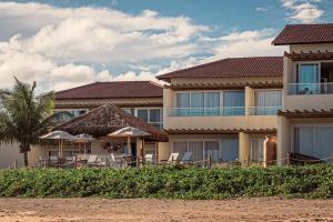 a resort on the beach with chairs and umbrellas at Pousada Aysú in Japaratinga