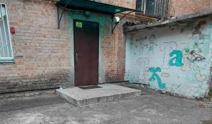 a brick building with a door with graffiti on it at Corona 11three-bedroom apartment in Cherkasy