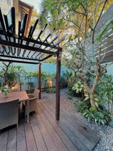 a wooden deck with a table and a wooden pergola at 3BR Villa mit Pool, Villa Jovino, Jameja Kerobokan in Kerobokan