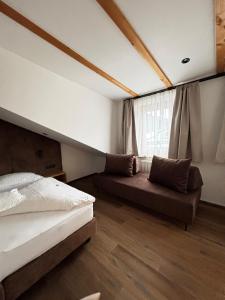 a bedroom with two beds and a couch and a window at Hotel Laerchenhain in San Valentino alla Muta