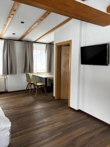 a room with a table and a tv on a wall at Hotel Laerchenhain in San Valentino alla Muta