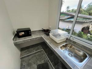 Una encimera de cocina con un fregadero y una ventana. en Chaloklum Garden House, en Ko Pha Ngan