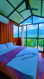 a bed in a room with a large window at Alpine Zenith - Luxury Wooden Cottages in Meppādi