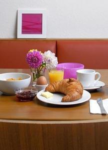 a table with a croissant and a plate of food at Business & Budget Hotel Tessin in Munich