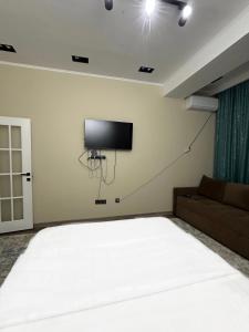 a bedroom with a large bed and a flat screen tv at Однушка в Асанбае in Bishkek