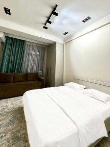 a bedroom with a large white bed and a couch at Однушка в Асанбае in Bishkek