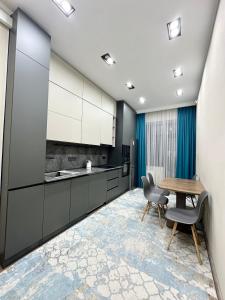 a kitchen with white cabinets and a wooden table and chairs at Однушка в Асанбае in Bishkek