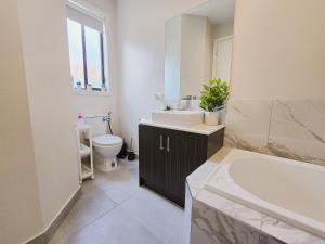 Modern 4BR Home Spacious & Family Friendly في Melton South: حمام مع حوض وحوض استحمام ومرحاض +8 صور