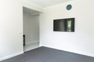 Modern 4BR Home Spacious & Family Friendly في Melton South: غرفة فارغة مع تلفزيون بشاشة مسطحة على الحائط