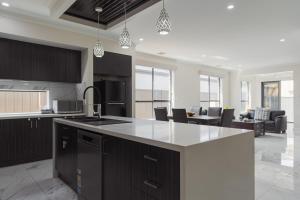 Modern 4BR Home Spacious & Family Friendly في Melton South: مطبخ مع دواليب سوداء وجزيرة مطبخ