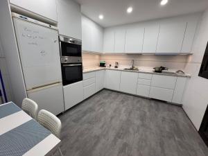 Una cocina con gabinetes blancos y un refrigerador blanco. en Estudio Las Rozas de Madrid, en Las Rozas de Madrid 3 fotos más