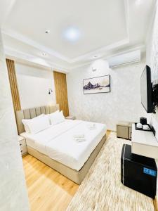 a bedroom with a white bed and a television at The Moonya Hotel in Samarkand