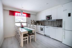 een keuken met witte kasten en een tafel en stoelen bij Santas Duplex II in Rovaniemi