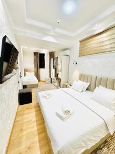 een slaapkamer met een groot wit bed en een televisie bij The Moonya Hotel in Samarkand