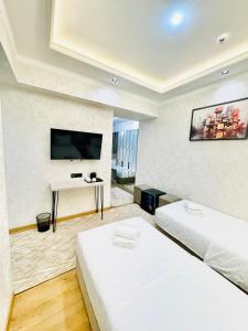 2 bedden in een kamer met een tv en een bureau bij The Moonya Hotel in Samarkand