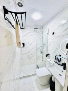 een witte badkamer met een wastafel en een douche bij The Moonya Hotel in Samarkand