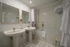 een witte badkamer met 2 wastafels, een bad en een wastafel bij Le Mirage De Watermolen Kasterlee in Kasterlee