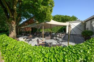 Le Mirage De Watermolen Kasterlee في كاستيرلي: فناء مع طاولات وكراسي ومظلة