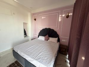 a bedroom with a large bed with a black headboard at The White Lotus Homestay in Dharmsala