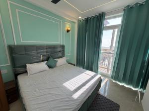 a bedroom with a bed with green curtains and a window at The White Lotus Homestay in Dharmsala