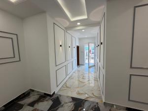 a hallway with white walls and marble floors and a door at The White Lotus Homestay in Dharmsala