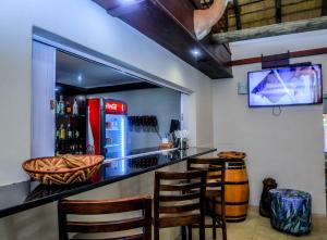 a bar in a restaurant with chairs and a tv at Manong Game Lodge in Lobatse