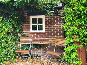 two benches sitting in front of a brick building with a window at Escape the Ordinary in Piddletrenthide