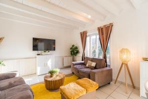 ein Wohnzimmer mit zwei Sofas und einem Fernseher in der Unterkunft Le Refuge de la Clarté, draps et serviettes inclus in Perros-Guirec