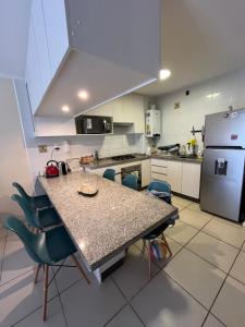 Cómodo Depto en bosques de la candelaria في ألغاروبو: مطبخ مع طاولة وكراسي وثلاجة