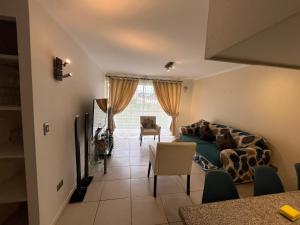 Cómodo Depto en bosques de la candelaria في ألغاروبو: غرفة معيشة مع أريكة وكرسي