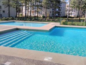 Cómodo Depto en bosques de la candelaria في ألغاروبو: حمام سباحة بمياه زرقاء في مبنى +7 صور