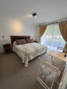 Cómodo Depto en bosques de la candelaria في ألغاروبو: غرفة نوم بها سرير وطاولة ونافذة