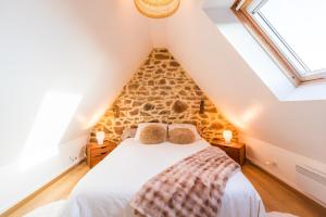 ein Schlafzimmer mit einem Bett mit einer Steinwand in der Unterkunft Le Refuge de la Clarté, draps et serviettes inclus in Perros-Guirec