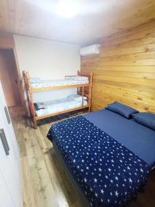 サン・フランシスコ・ド・スルにあるCasa de Praiaのベッドと青いベッドカバーが掛けられた二段ベッドのある部屋