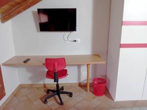 Casa Happy - La mansarda del sorriso con parcheggio privato a Valcorrente في بيلباسو: مكتب وكرسي احمر وتلفزيون على جدار