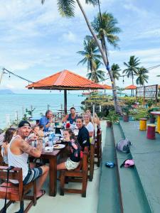 Panglima Resort Semporna في سيمبورنا: مجموعة من الأشخاص يجلسون في مطعم على الشاطئ