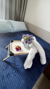 Flat com Hidromassagem Privativa no Centro De Porto de Galinhas - Sol e Mar Residence في بورتو دي غالينهاس: صينية مع باقة ورد على سرير