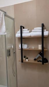 y baño con estante con toallas y ducha. en 50 Passi dal Duomo, en Marcianise