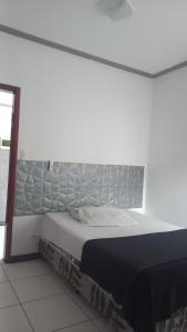 una cama en una habitación con una pared blanca en Pousada na Orla, Atalaia, en Aracaju