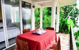 a table on a porch with a red tablecloth on it at Rokky Hill Cottage Ella in Ella