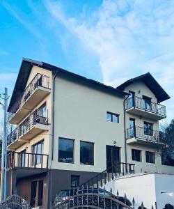 Un edificio blanco con balcones a los lados. en Pensiunea La Vio, en Grozavesti