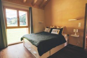 Appartement Cosy & Calme au Cœur de la Gruyère في Jaun: غرفة نوم بها سرير ونافذة كبيرة