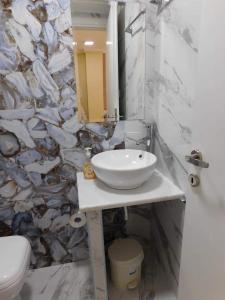 uma casa de banho com um lavatório branco e uma parede de pedra em Corner Studios em Perea