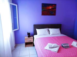 een paarse slaapkamer met een bed met handdoeken erop bij OINO APARTMENT in Corfu-stad