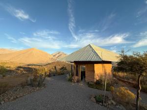 Un edificio en el desierto con montañas al fondo. en Santuario Hexágono Mamalluca, en Vicuña