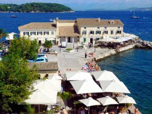 een resort aan het water met witte parasols bij OINO APARTMENT in Corfu-stad
