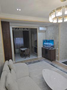 un soggiorno con un divano e una televisione di Prestige Apartament a Tashkent