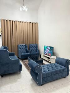 Una sala de estar con dos sofás azules y un televisor. en J&N Homestay, en Skudai